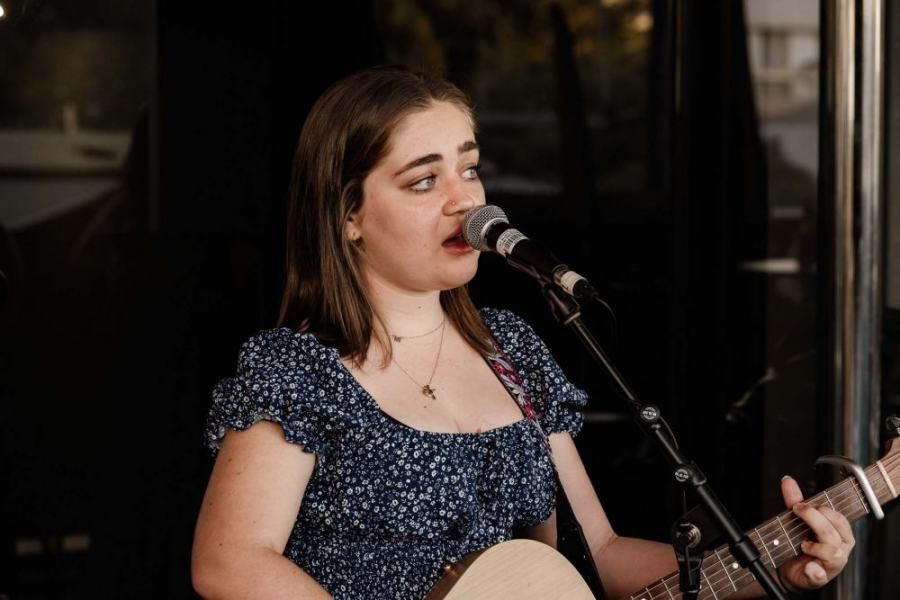 A woman is singing into a microphone while holding a guitar.