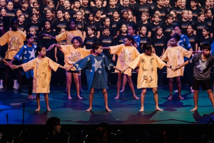 A group of children are holding hands on a stage.