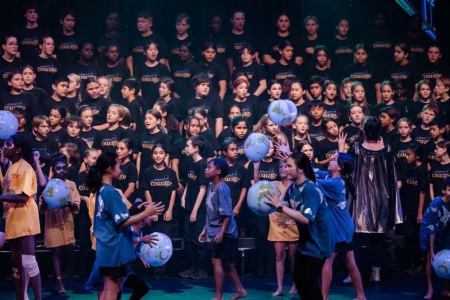 A large group of children are playing with balloons on a stage.