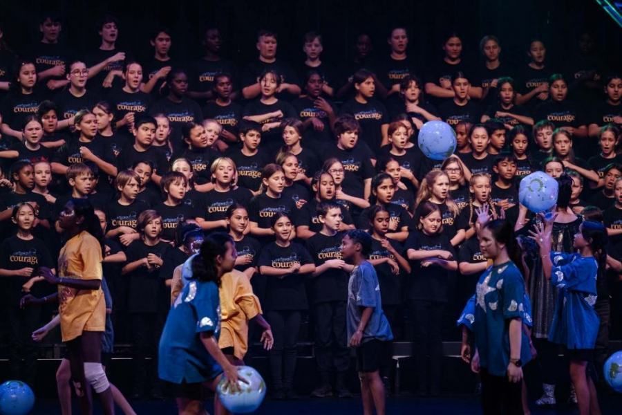 A group of children are playing frisbee in front of a large choir.