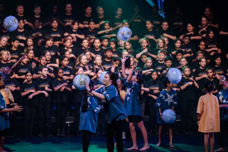 A large group of children are playing with balloons on a stage.