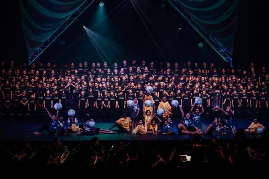 A large choir is performing on a stage in front of a crowd.