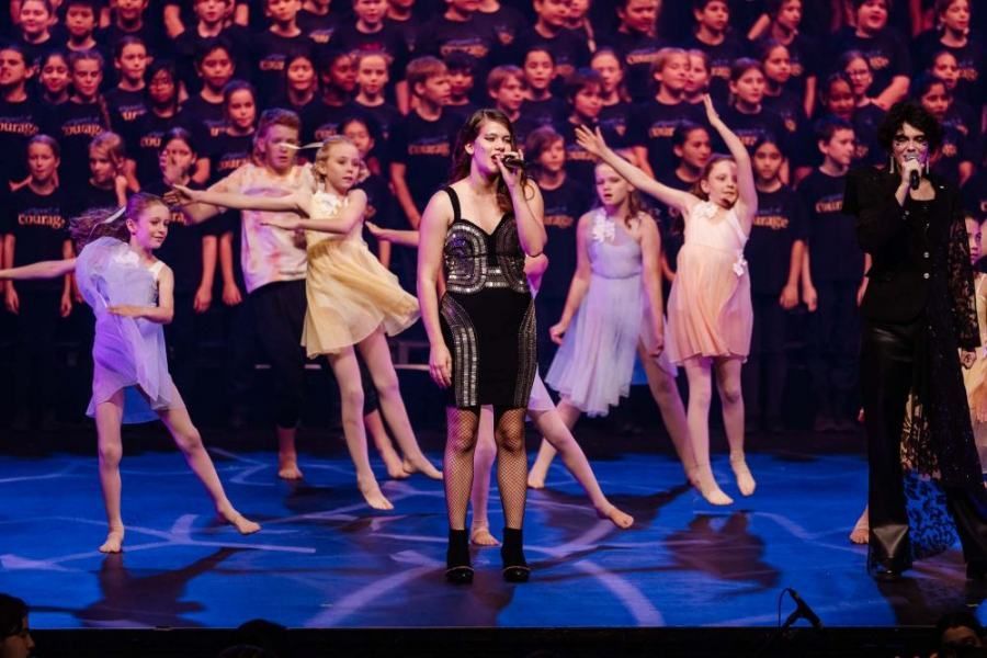 A group of young girls are dancing and singing on a stage.