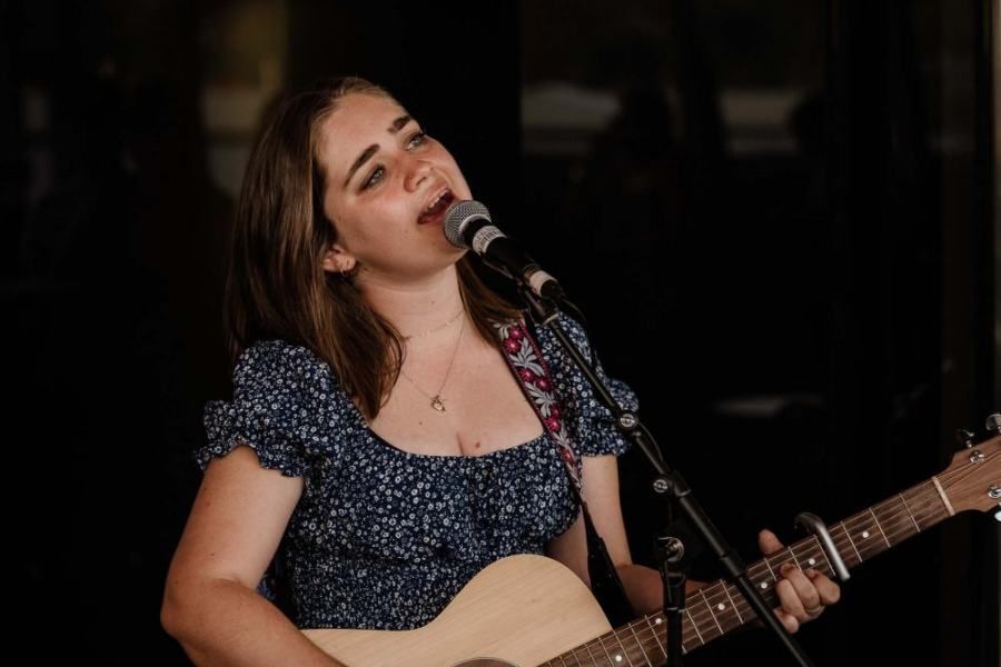A woman is singing into a microphone while holding a guitar.
