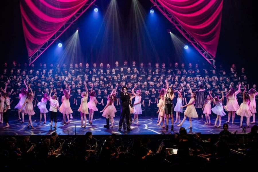 A large group of people are dancing on a stage.