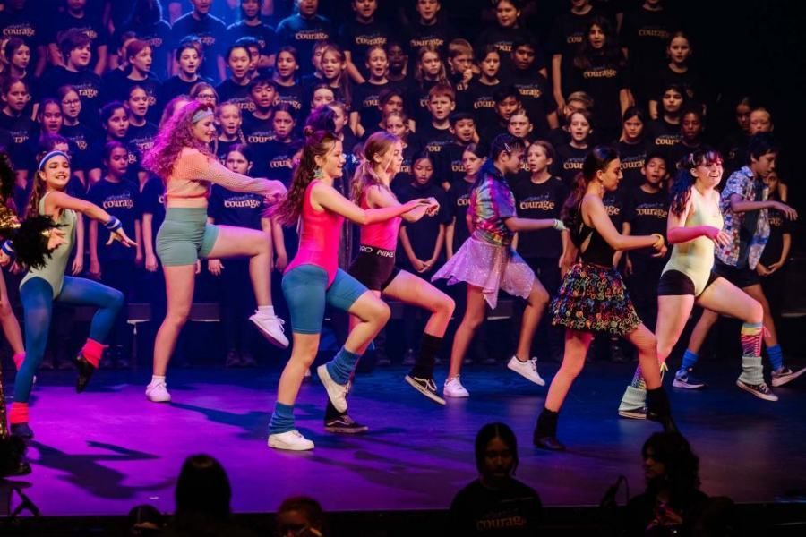 A group of young girls are dancing on a stage in front of a crowd.