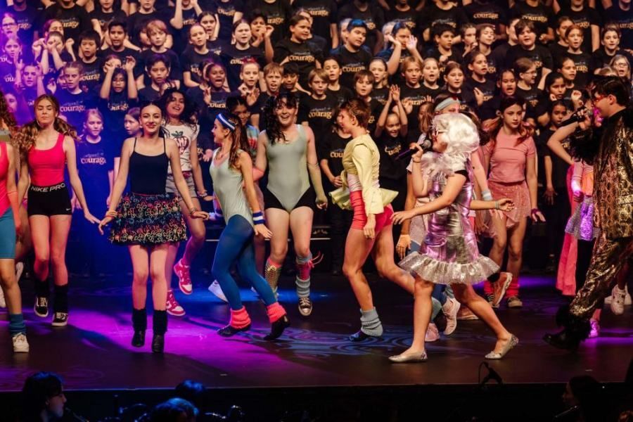 A group of young girls are dancing on a stage in front of a crowd.
