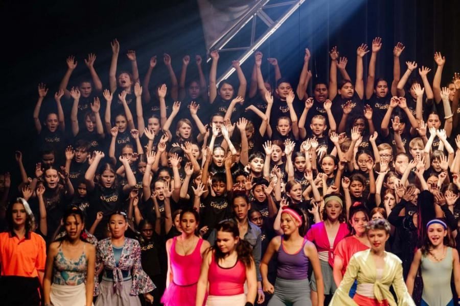 A large group of people are standing on a stage with their hands in the air.
