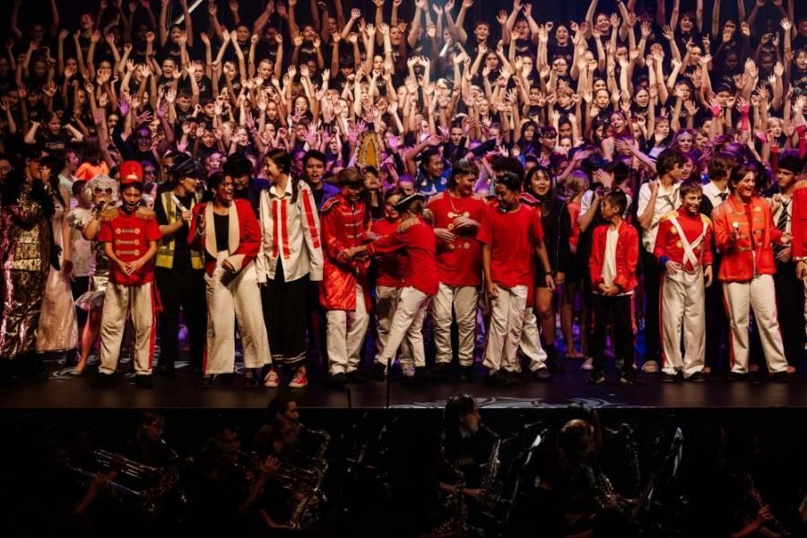 A large group of people are standing on a stage with their hands in the air.