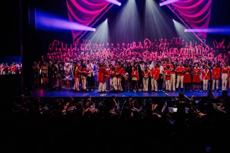 A large group of people are standing on a stage in front of a crowd.