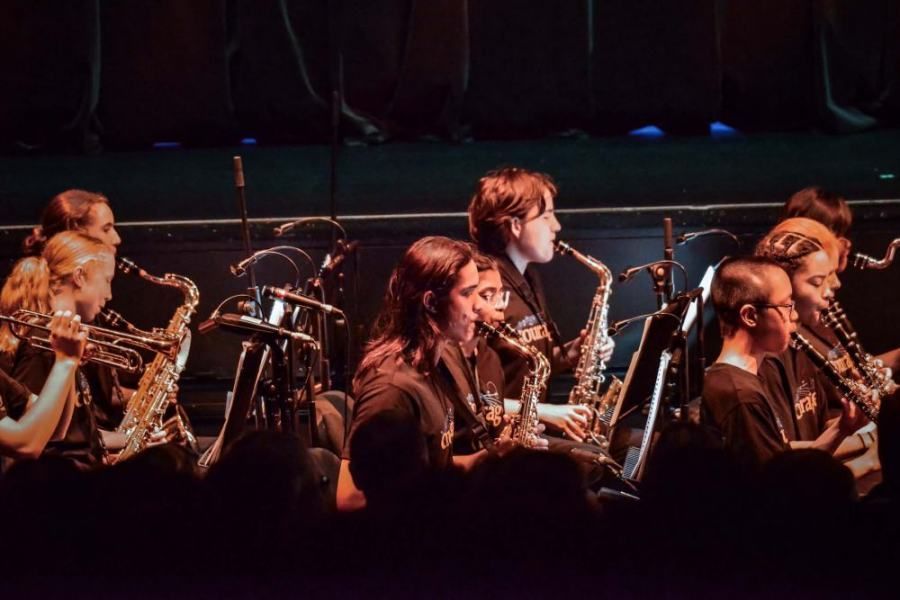 A group of people are playing saxophones on a stage