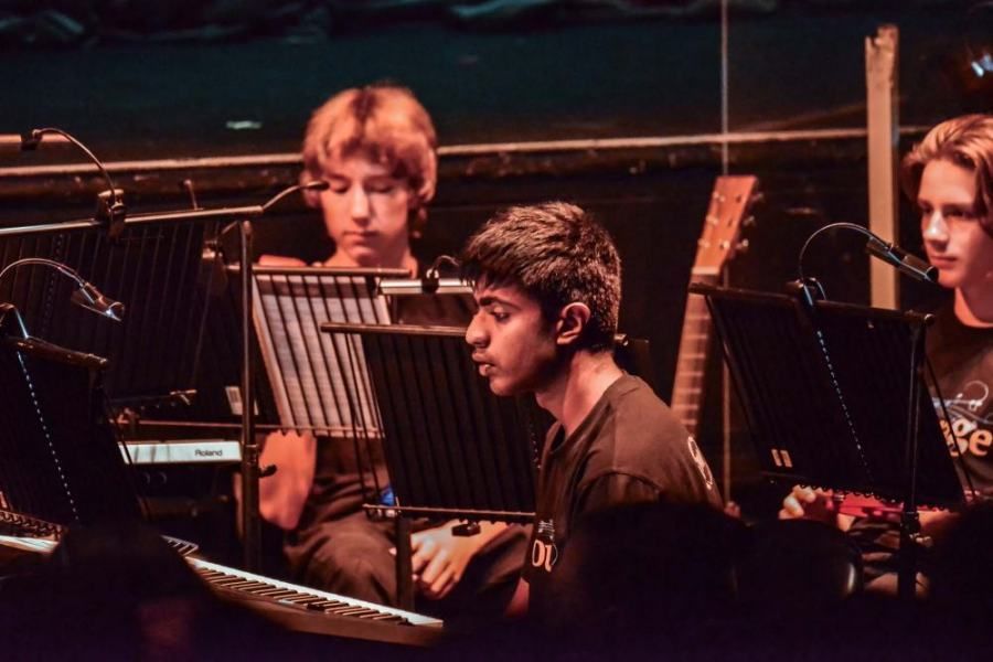A group of young men are playing instruments and singing into microphones