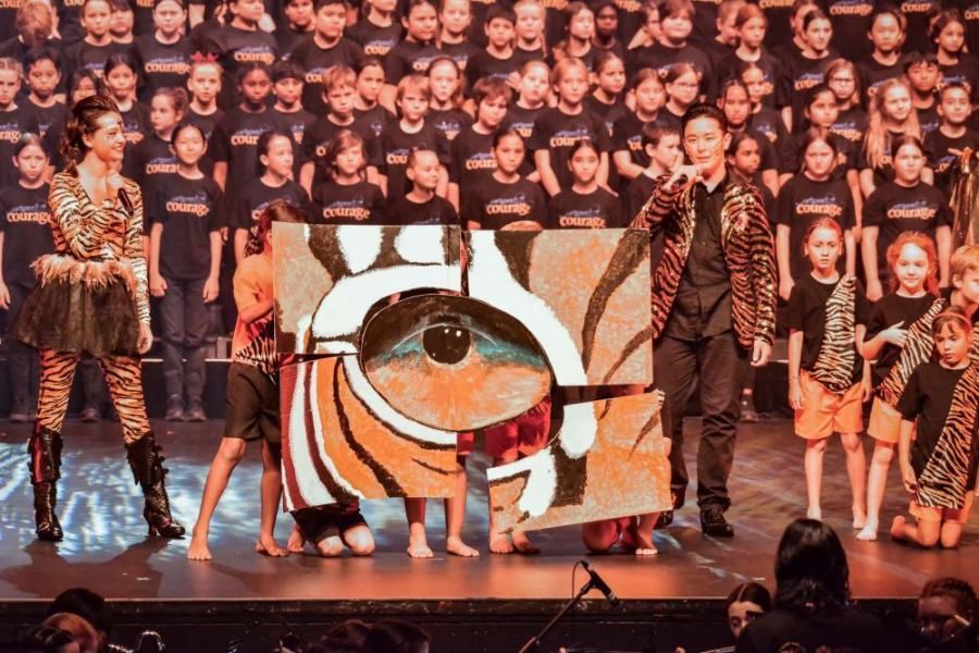 A group of people are standing on a stage holding a large painting of an eye.