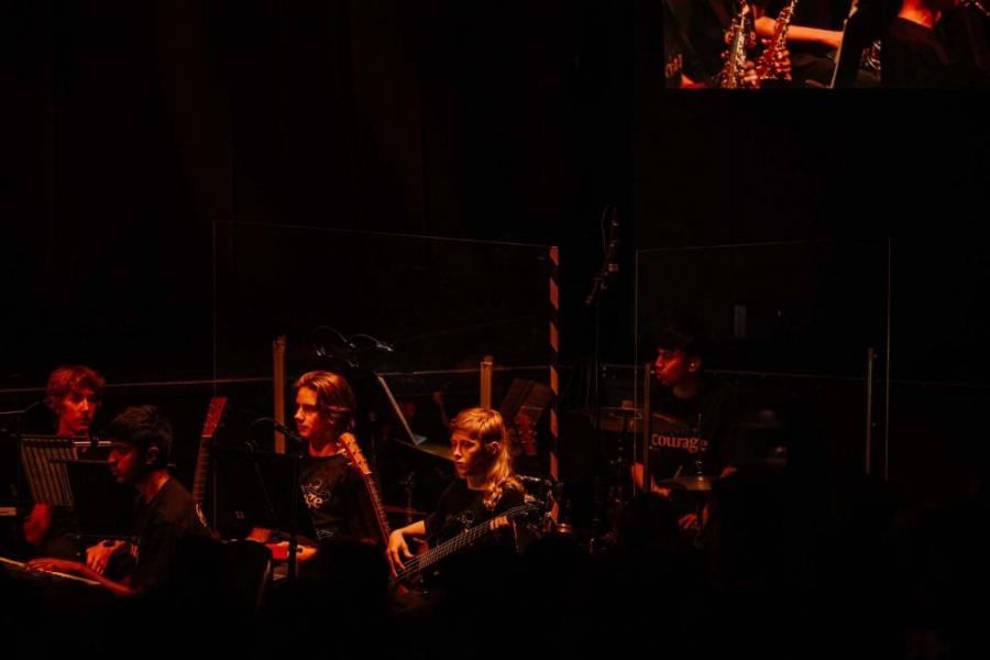 A group of people are playing instruments on a stage in a dark room.
