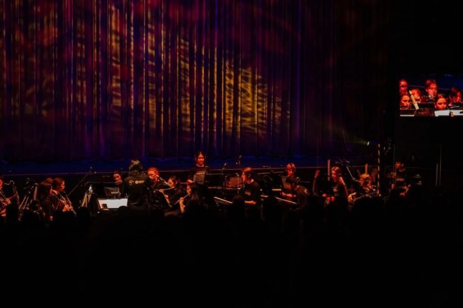 A group of people are playing instruments on a stage in a dark room.