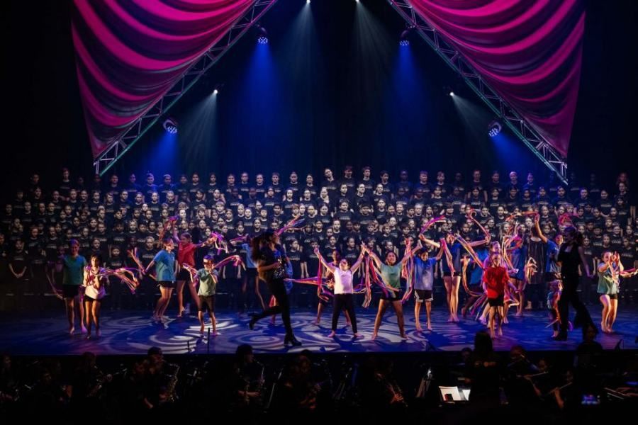 A large group of people are dancing on a stage.