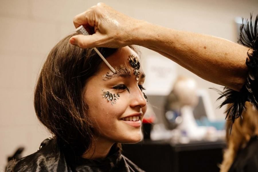 A woman is getting her face painted by a makeup artist.