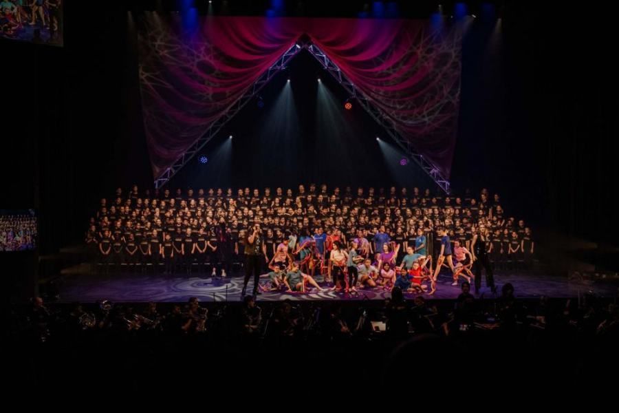A group of people are dancing on a stage in front of a crowd.