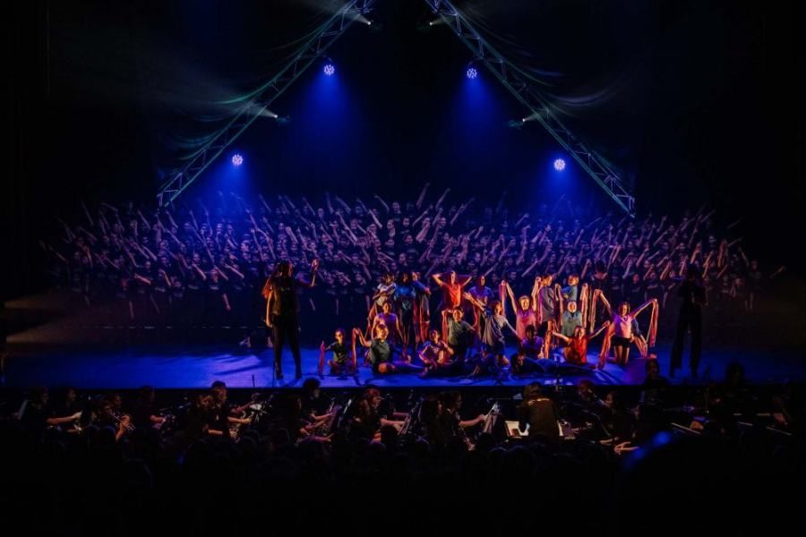 A large group of people are standing on a stage in front of a crowd.