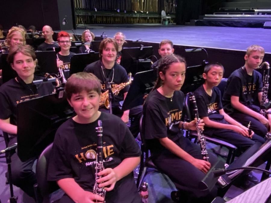 A group of young musicians wearing black shirts that say home