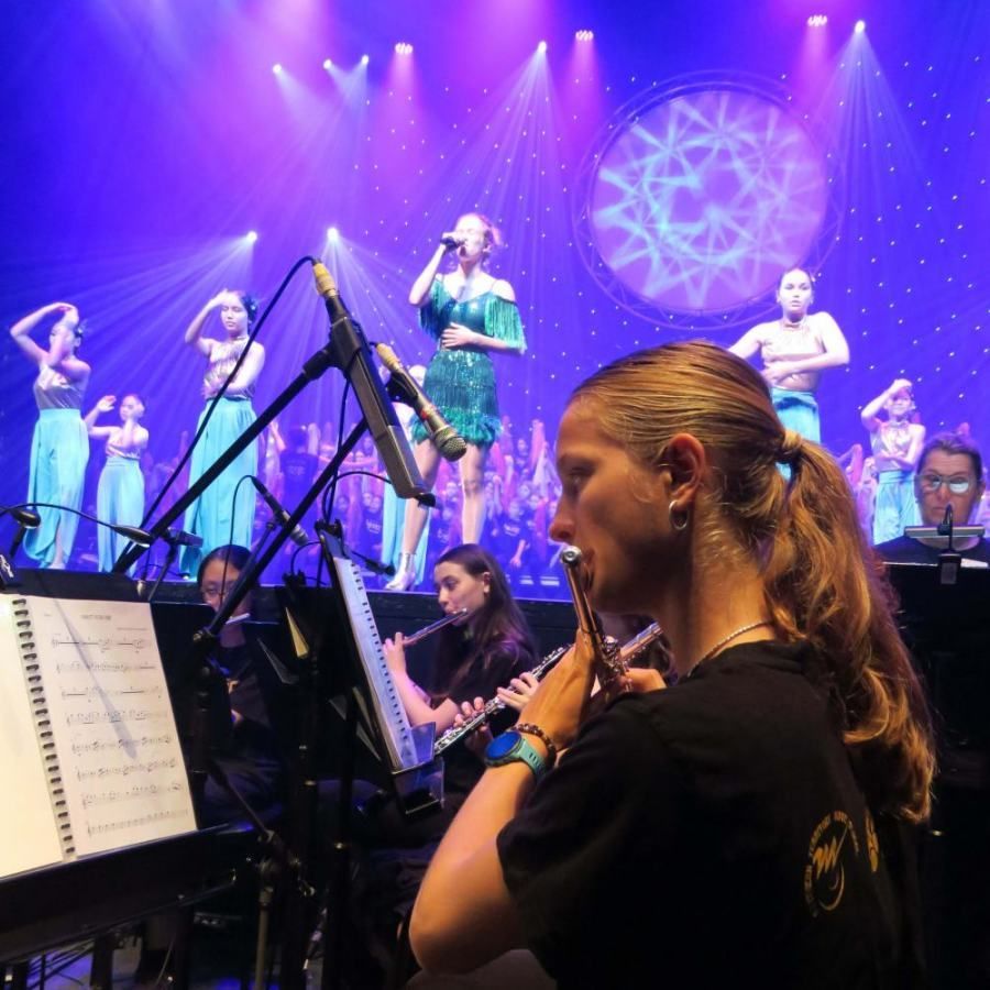 A woman playing a flute in front of a choir