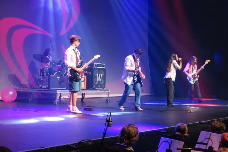 A group of people are playing guitars and singing on a stage.