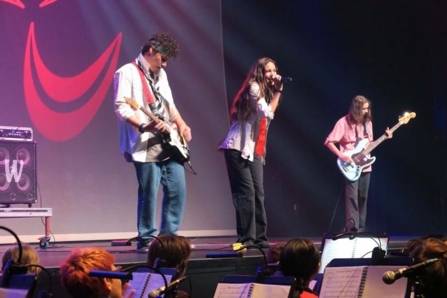 A man playing a guitar and two women singing on stage