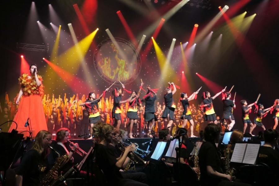 A group of people are dancing on a stage in front of an orchestra.