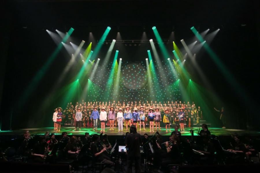 A large group of people are standing on a stage under green lights.