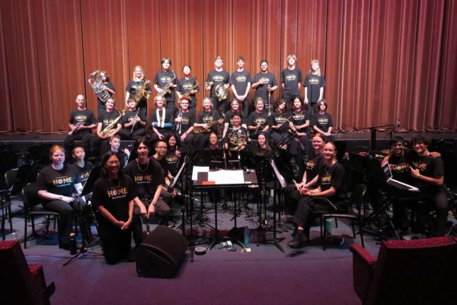 A large orchestra is posing for a picture on a stage.