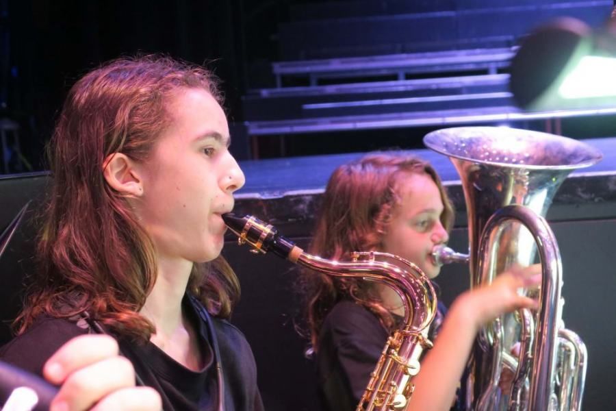 A boy is playing a saxophone and a girl is playing a tuba.