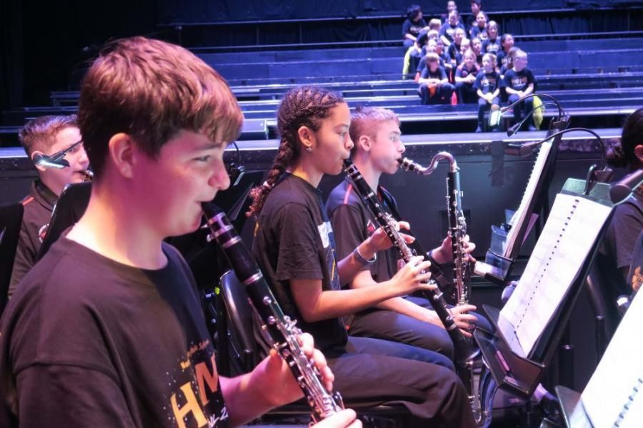 A group of young people are playing clarinets and saxophones in an orchestra.