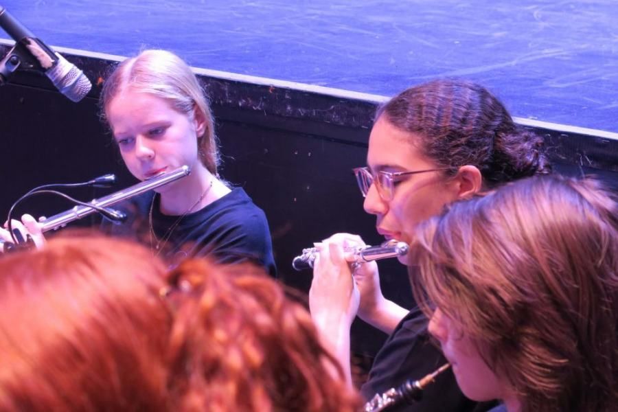 A group of young girls are playing flutes on a stage.