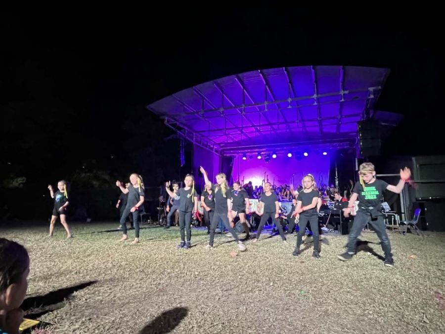 A group of children are dancing on a stage at night.