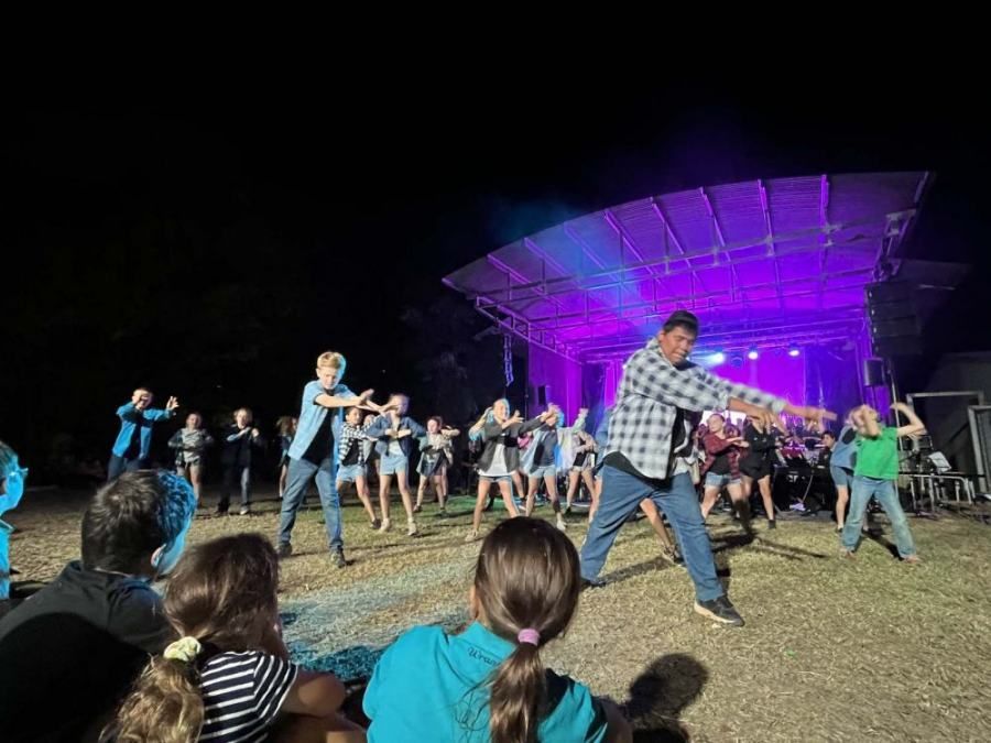 A group of people are dancing on a stage at night.