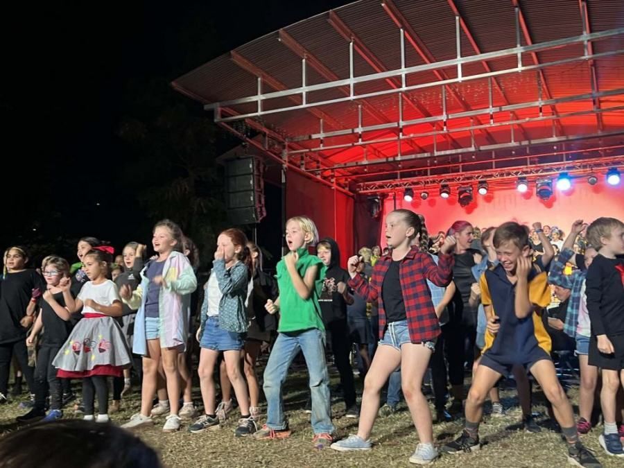 A group of children are dancing on a stage at night.