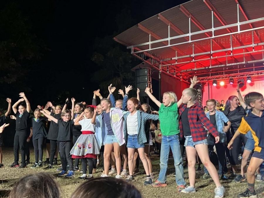 A group of children are dancing on a stage at night.