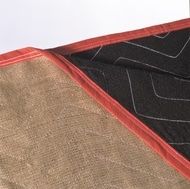 Tan and black quilted blanket with red trim.
