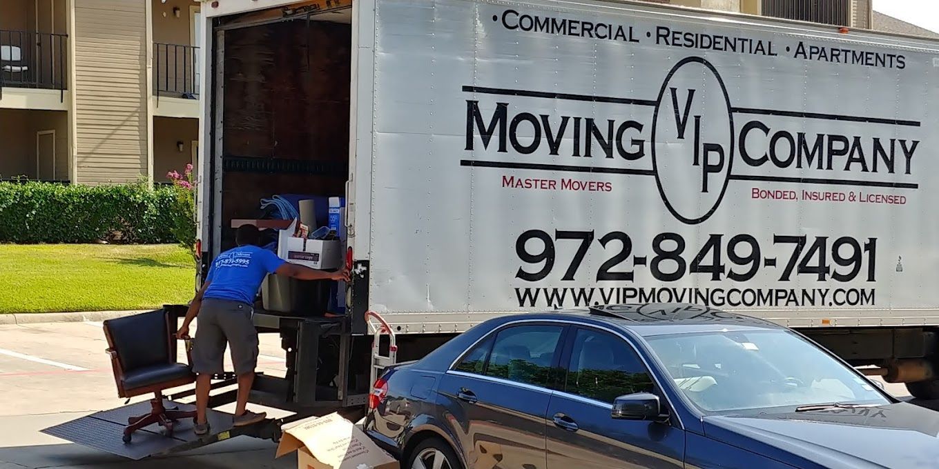 A moving company truck is parked next to a car.