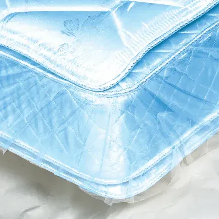 Blue mattress corner in plastic, close-up, quilted pattern, white seam.