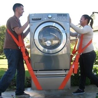 Two people using lifting straps to move a washing machine outdoors.