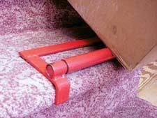 Red stair tool wedged under cardboard box on floral fabric.
