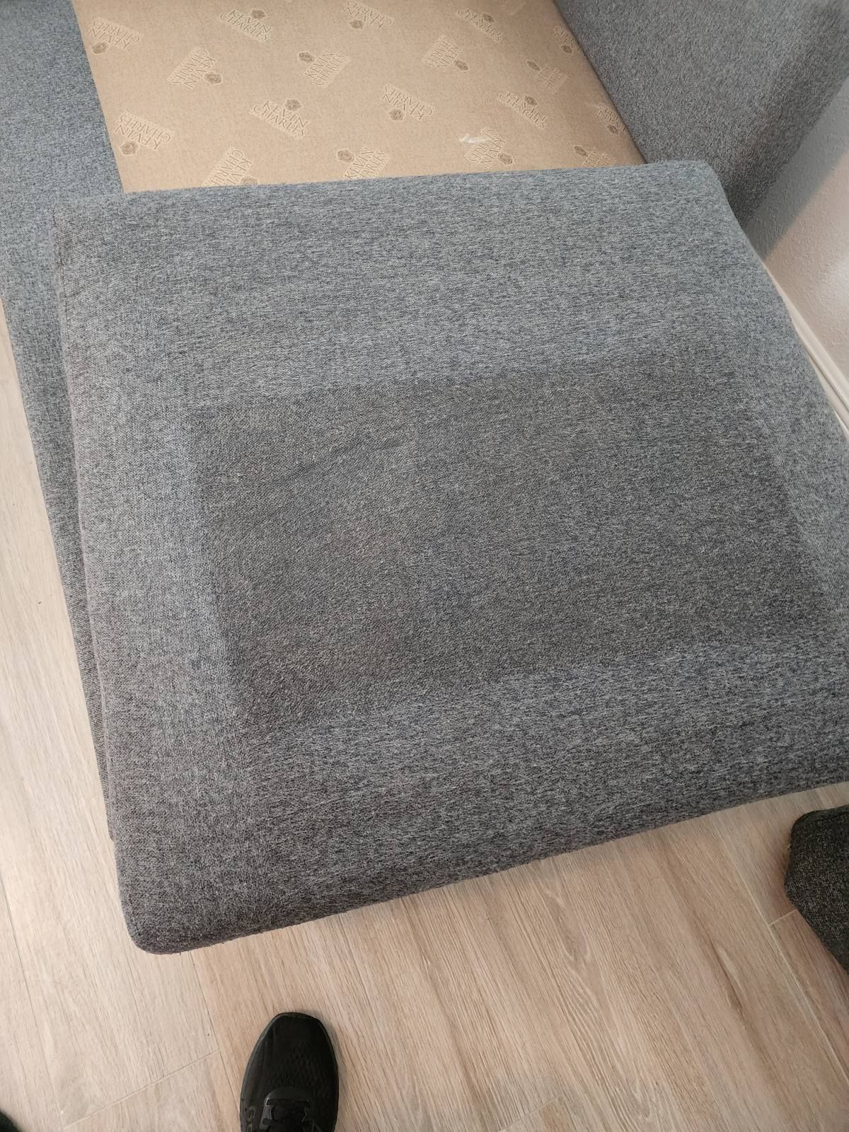 Gray upholstered ramp or step over a beige floor; a black shoe is visible at the bottom.