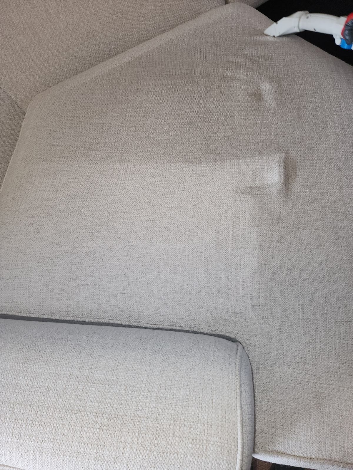 Beige sofa cushion with a flat rectangular patch on the backrest and a white object at the top right