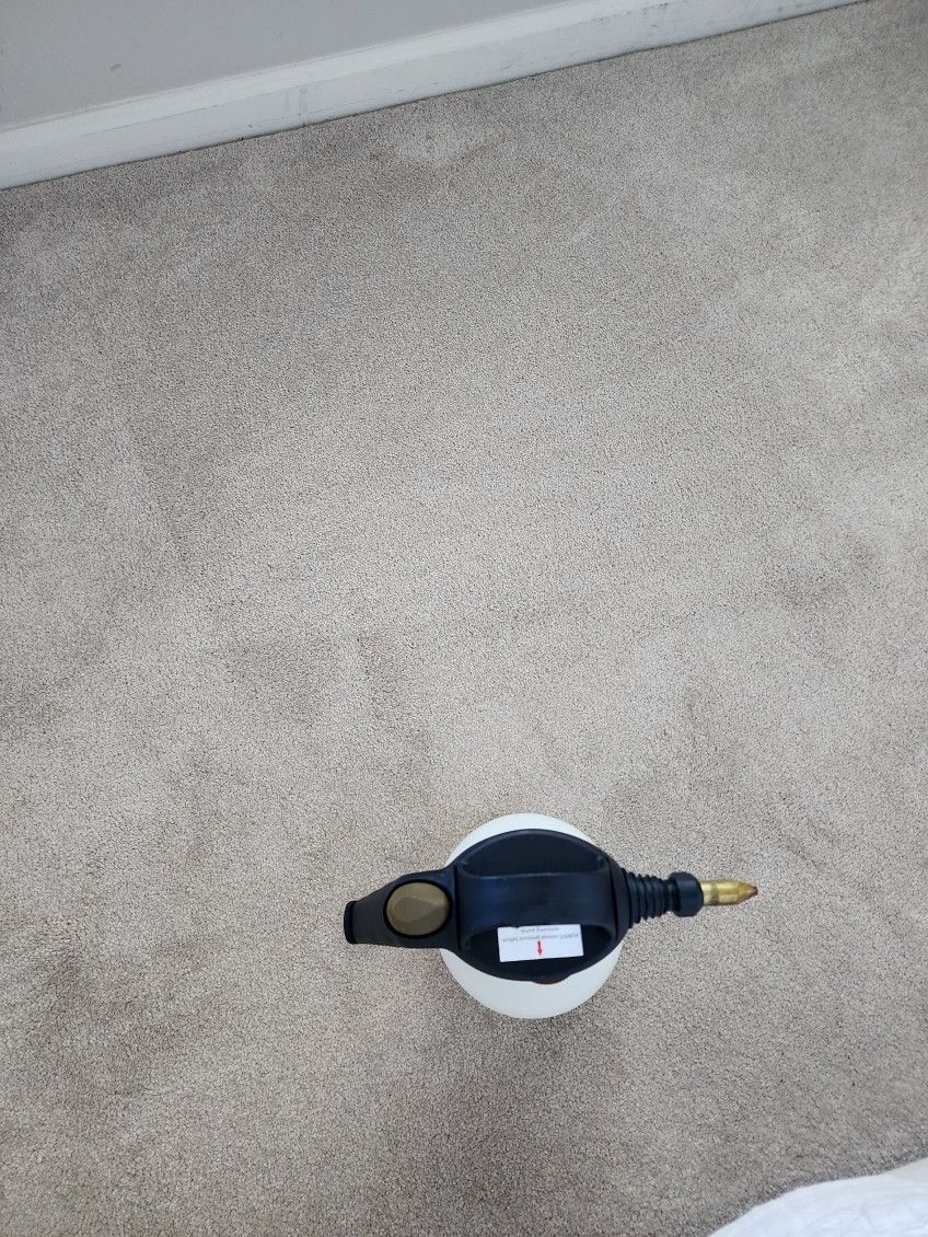 Overhead view of a black device with gold ends on beige carpet, centered in a white circular base