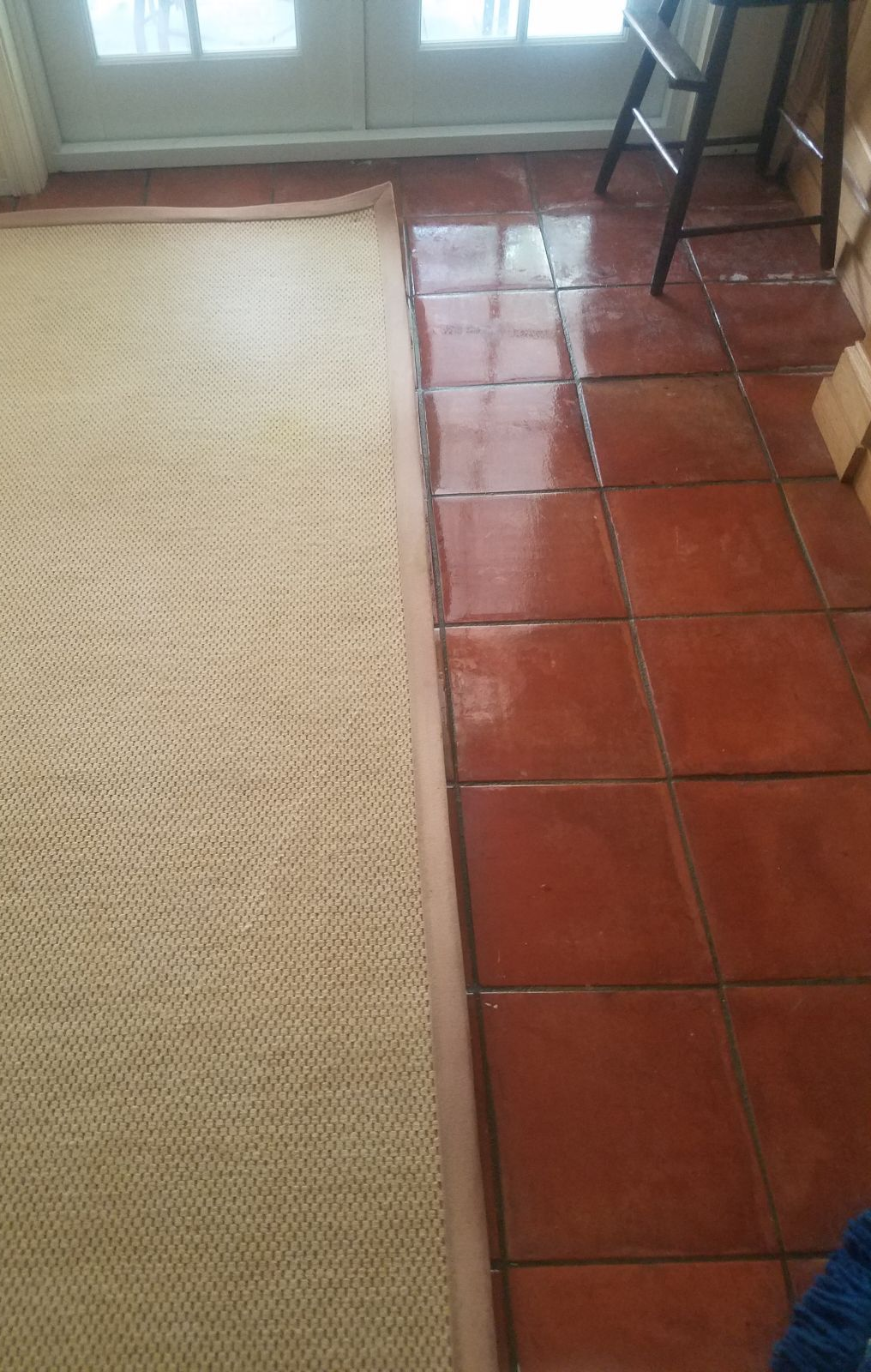 Tiled floor beside a beige carpet near a window, with a black chair in the corner