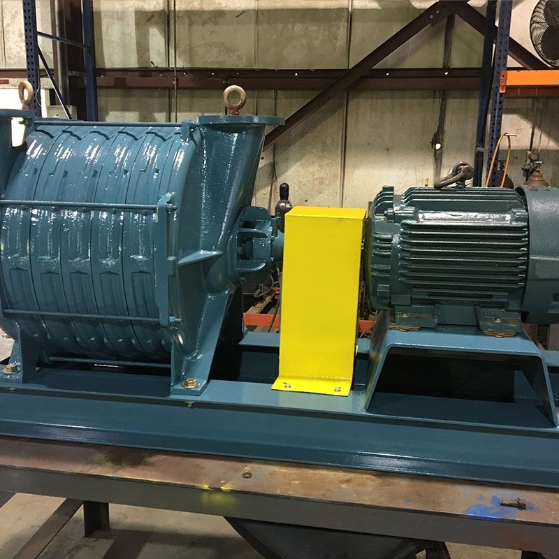 Industrial machine with blue housing, yellow guard, and green motor mounted on a metal base in a workshop