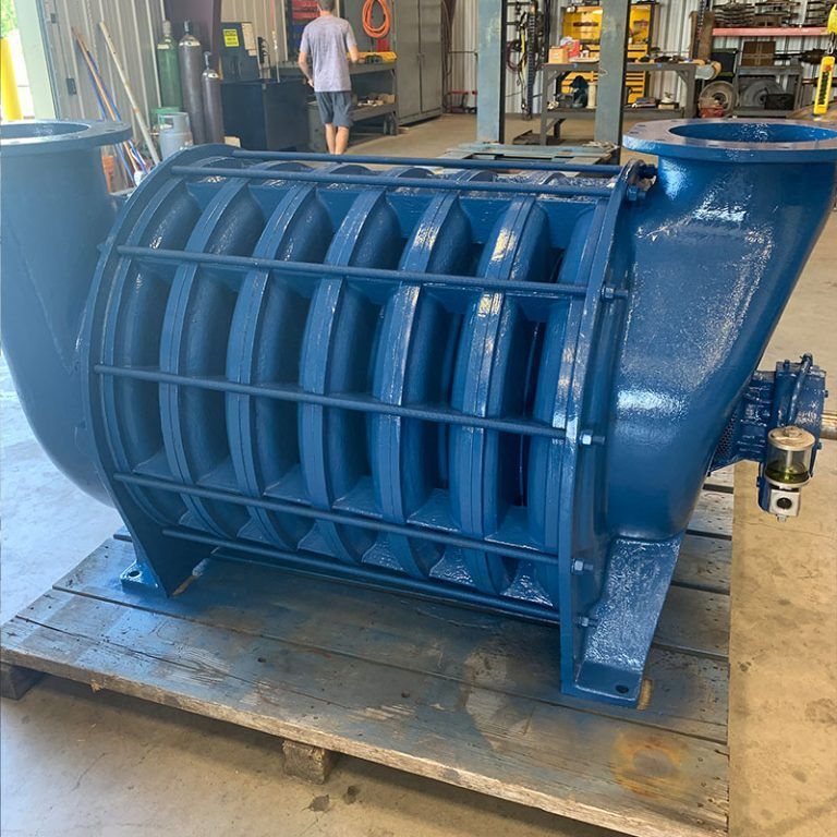 Large blue industrial metal pump or fan housing on a pallet in a workshop