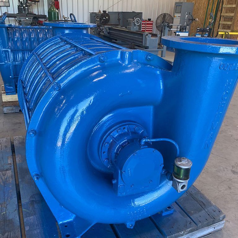 Blue industrial pump on a pallet in a workshop, with a large circular housing and attached motor.