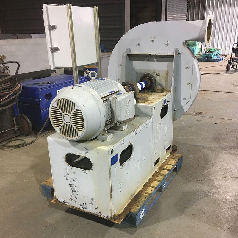 Large white industrial motor and pump assembly on a wooden pallet in a workshop.